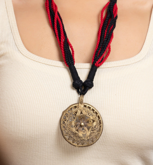 a woman wearing a necklace with a medallion on it