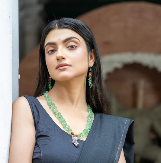 a woman wearing a green necklace and earrings